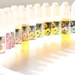 An e-cigarette and bottles of vape liquid arranged on a table.