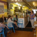 The owner of a small independent shop serving a customer at the counter